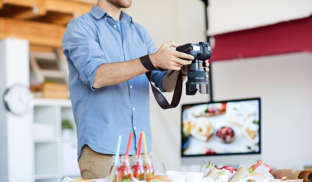 Mid-section portrait of young photographer taking photos of food while working in studio, copy space