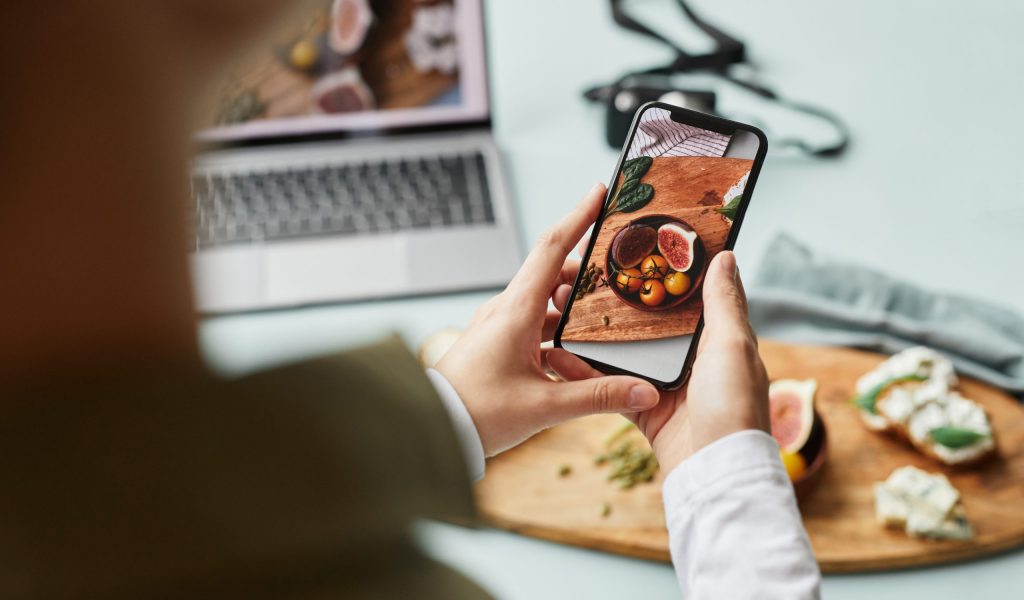 Close up of young woman taking aesthetic photo of food using smartphone for social media, copy space